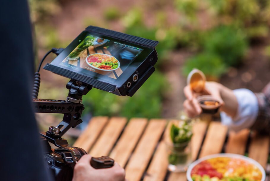 Close view of a photographer shooting a poke bowl on a professional camera with external display in a park